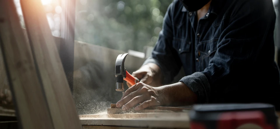 Atelier de menuiserie avec quatre artisans collaborant autour d'un établi en bois massif