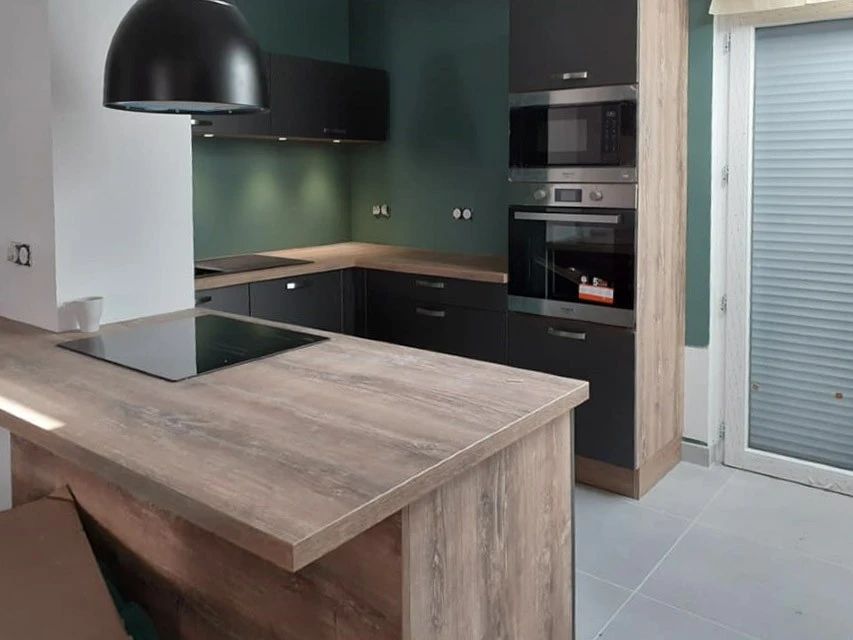 Atelier de menuiserie avec deux artisans en tabliers travaillant sur un projet commun