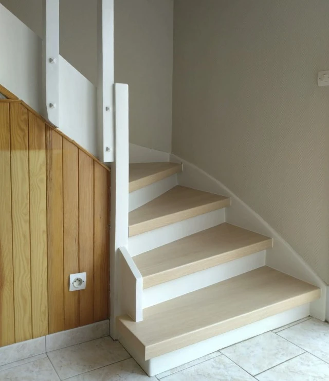Escalier intérieur moderne en bois clair avec rampe design minimaliste, sol carrelage beige poli, murs blancs épurés