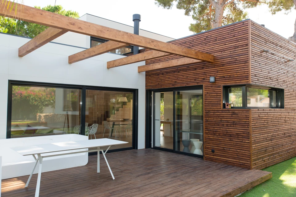 Intérieur résidentiel lumineux avec grandes baies vitrées à carreaux et porte-fenêtre double battant donnant sur terrasse extérieure