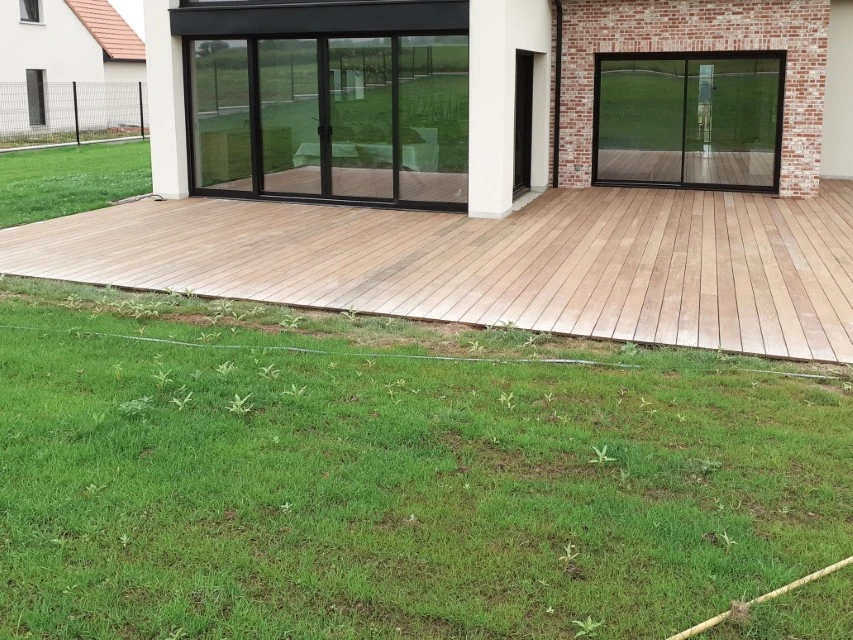 Chantier de construction d'une terrasse en bois sur pilotis avec structure de couverture en cours d'assemblage