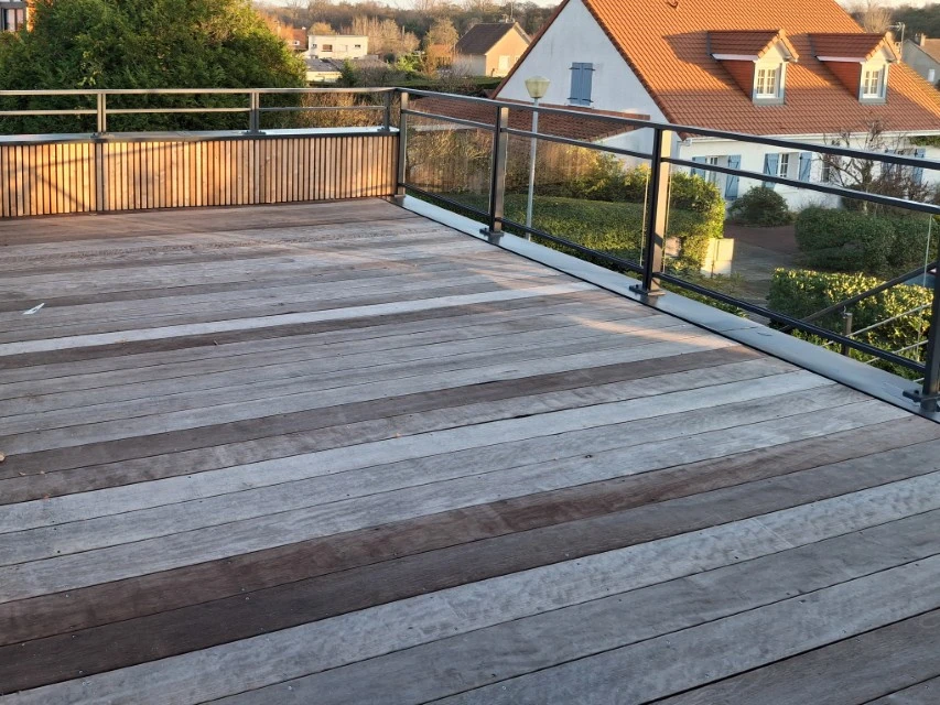 Chantier extérieur de construction d'une terrasse en bois devant maison résidentielle à bardage jaune