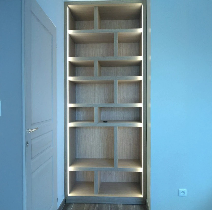 Petit studio élégant avec salon ouvert sur la cuisine et la chambre derrière un mur en verre et éclairé